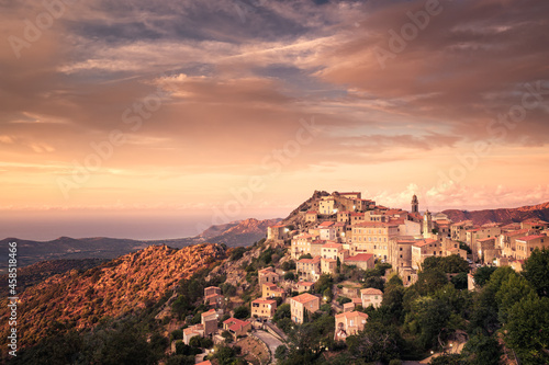 Sun setting on the remote mountain village of Speloncato in the Balagne region of Corsica with the Mediterranean sea in the distance
