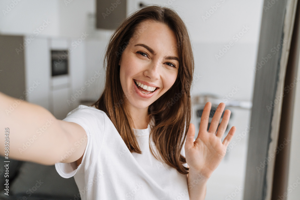 Young white woman smiling and gesturing while taking selfie photo Young white woman smiling and gesturing while taking selfie photo