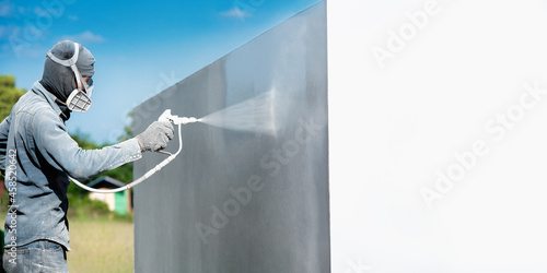 Airless Spray Painting, Worker painting on steel wall surface by airless spray gun for protection rust and corrosion. photo