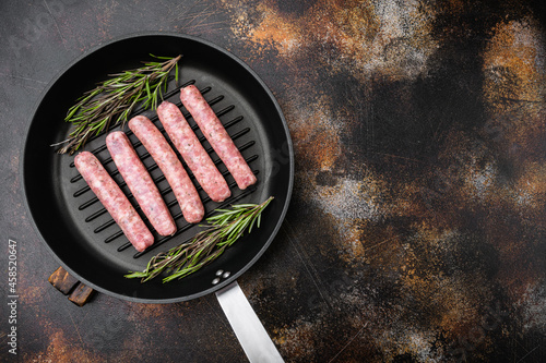 Fresh homemade sausages, on frying cast iron pan, on old dark rustic table background, top view flat lay, with copy space for text