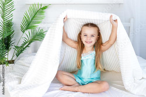 Fotografi a little girl child is playing under the blanket waking up in the morning at hom