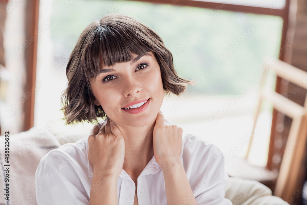 Photo of cute brunette hairdo young lady hands neck wear white shirt alone at home Photo of cute brunette hairdo young lady hands neck wear white shirt alone at home