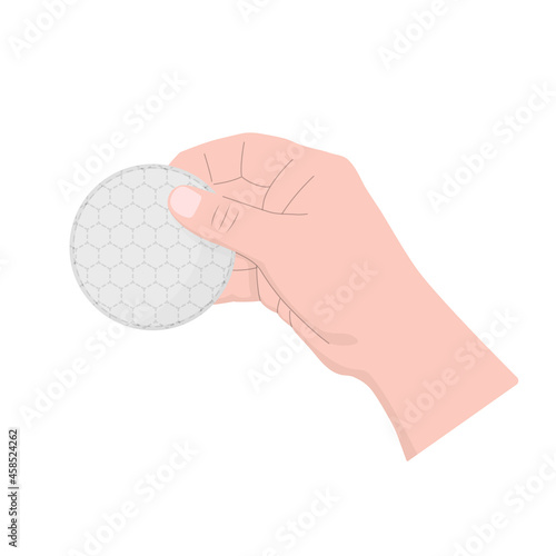 The hand holds a round cotton pad. Face care cosmetic.