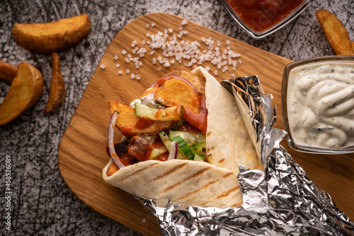 doner kebab, a shawarma in a pit of fresh vegetables and meat. with large spices. restaurant serving. on a dark background. for menus and ads