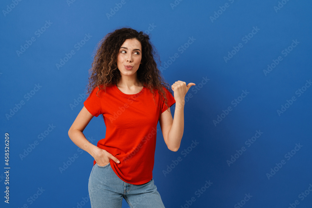 Fototapeta premium Young brunette woman with wavy hair looking and pointing finger aside
