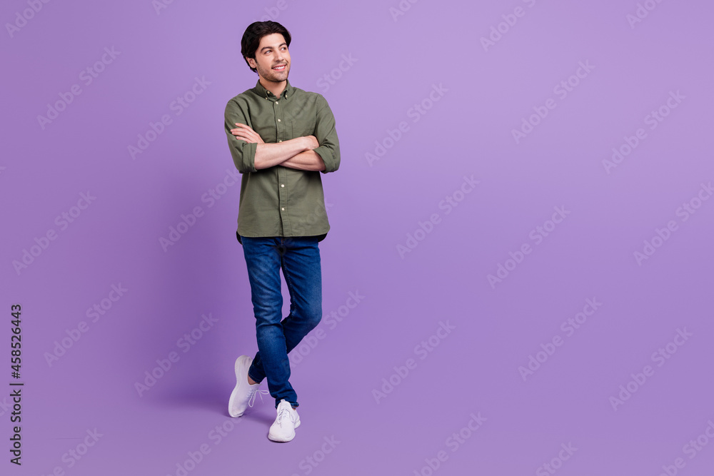 Full size photo of dreamy happy young man hold hands crossed look copyspace isolated on violet color background Full size photo of dreamy happy young man hold hands crossed look copyspace isolated on violet color background