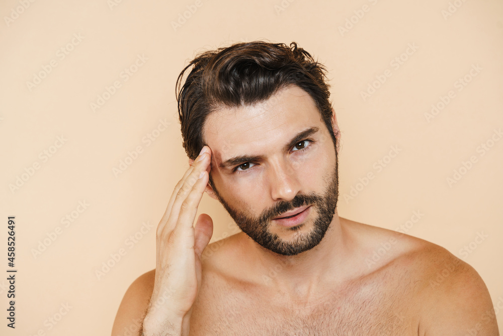 Obraz premium Young half-naked man rubbing his temple and looking at camera
