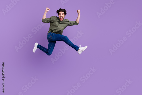 Full body photo of crazy cheerful happy young man jump up cool runn winner isolated on violet color background