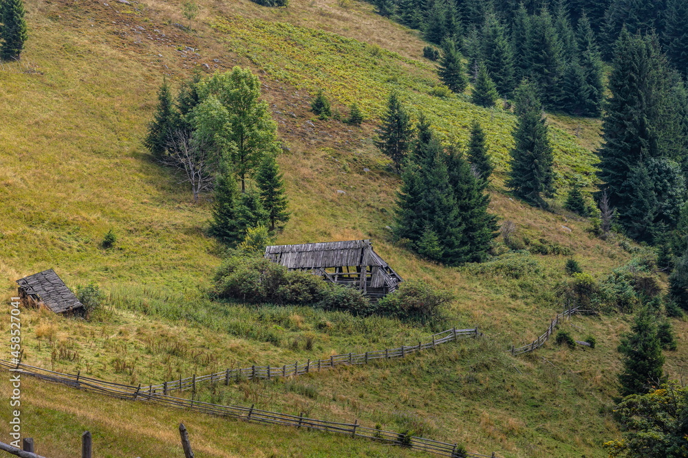 Abandoned buildings in the mountains, wooden houses against the background of rocks, the natural landscape, green meadows and forests Abandoned buildings in the mountains, wooden houses against the background of rocks, the natural landscape, green meadows and forests