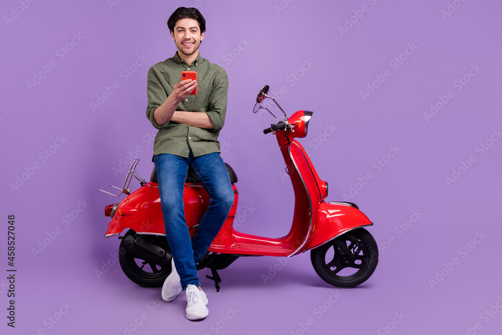 Full length photo of positive cheerful young man cool hold hand smartphone enjoy isolated on purple color background Full length photo of positive cheerful young man cool hold hand smartphone enjoy isolated on purple color background