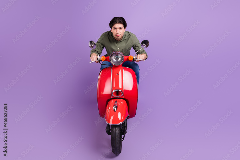 Full length photo of cool serious young man ride bike wear casual clothes isolated on violet color background Full length photo of cool serious young man ride bike wear casual clothes isolated on violet color background