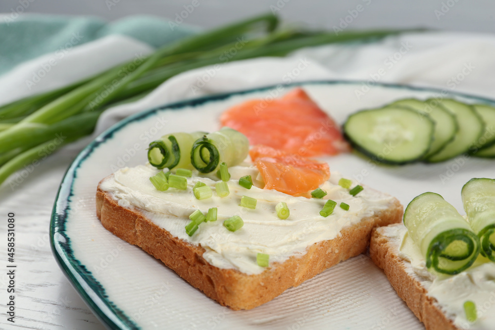 Toasted bread with cream cheese, salmon and cucumber on plate, closeup Toasted bread with cream cheese, salmon and cucumber on plate, closeup