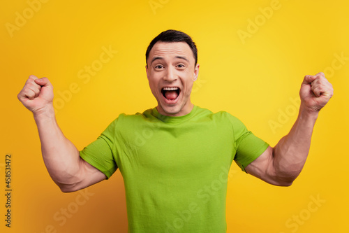 Portrait of cheerful astonished guy winner concept open mouth on yellow background