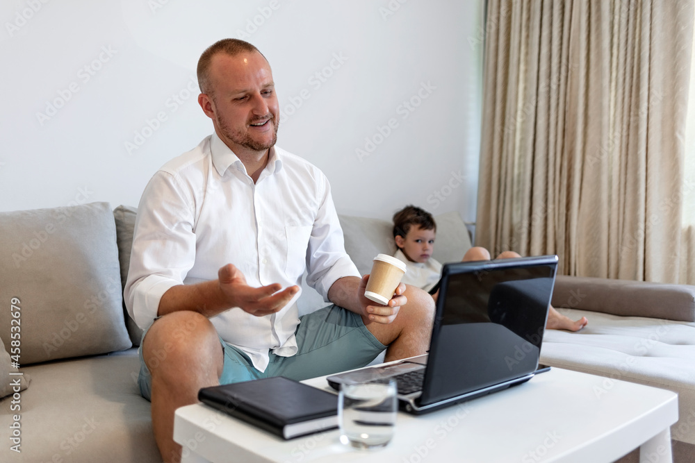 Cropped shot of a millennial generation father working from home with small children while in quarantine isolation during the COVID-19 health crisis. Little boy using tablet computer.