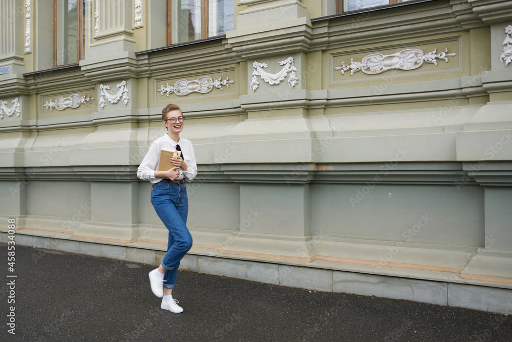 student with glasses walking around the city with a book communication