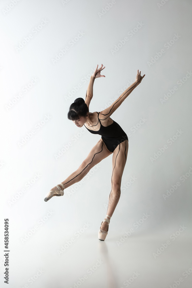 Japanese female ballet dancer, ballerina dancing isolated on light gray studio background. Art, motion, action, flexibility, inspiration concept.