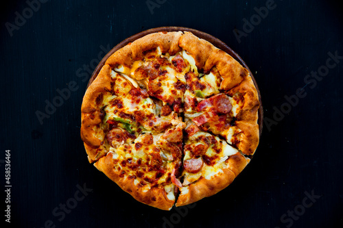 Top view of crispy pizza on black background