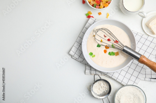 Flat lay composition with raw dough, candied fruits and other ingredients on white table, space for text