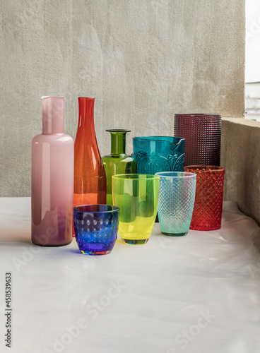 Many Different glass jar and glass cups and surface reflections on pink table cloth. Group of different glassware, Selective focus.