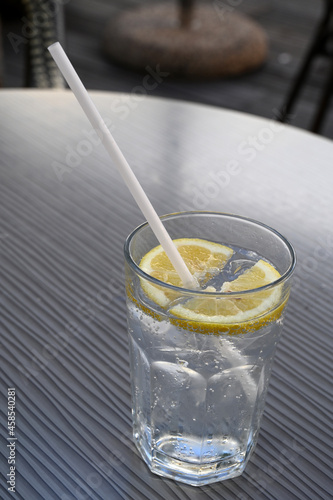 Verre d'eau gazeuse avec une rondelle de citron et une paille photo