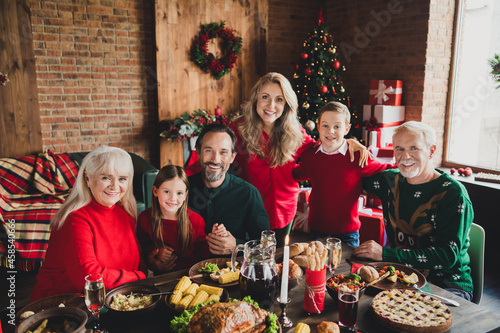 Photo of family portrait smile friends small childhood grandchildren pensioner retired grandparents sit table noel xmas indoors in house