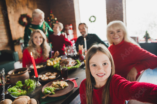 Photo portrait of smiling granddaughter taking selfie of family sitting at table celebrating christmas