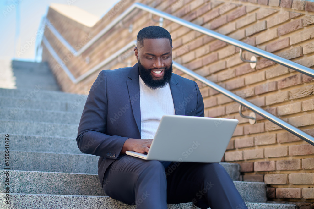 A picture of a dark-skinned man in a suit with a laptop A picture of a dark-skinned man in a suit with a laptop