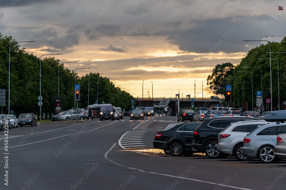 2020, July 11 - Riga, Latvia: Summertime. Road, parking and golden sunset in the city.