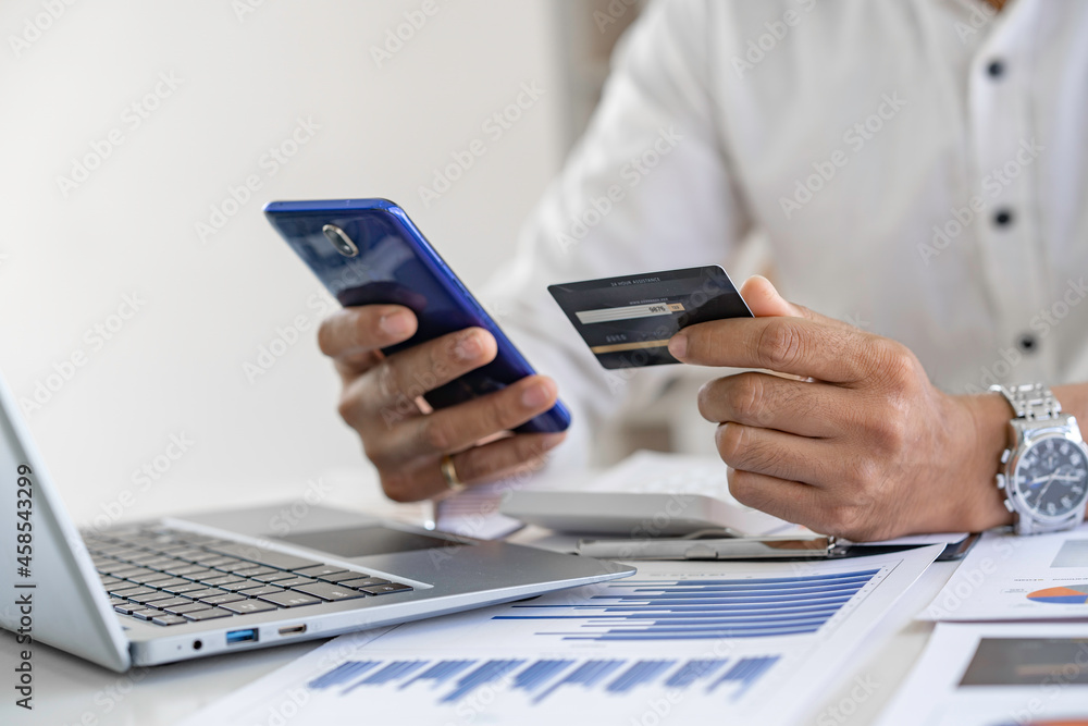 Man hands using smartphone and laptop computer for online shopping at home, Hand holding mobile phone with Payment Detail and credit card, online shopping concepts, Convenience online shopping Man hands using smartphone and laptop computer for online shopping at home, Hand holding mobile phone with Payment Detail and credit card, online shopping concepts, Convenience online shopping