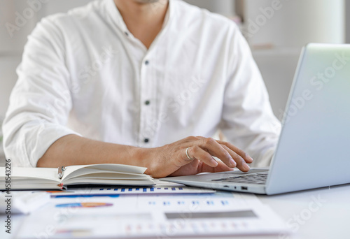 Businessman hands typing on laptop keyboard analyzing the graph at desk sales data and economic growth graph chart. Business strategy. Preparing report