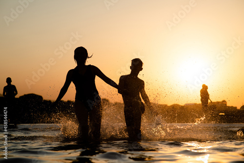 Happy kids running and splashing in the sea. Summer vacation and healthy lifestyle concept