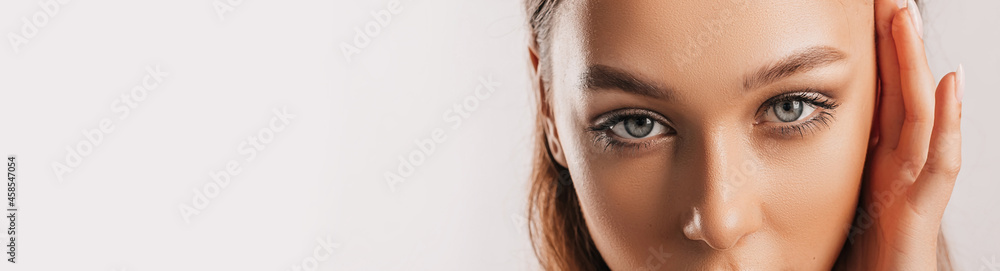 Fototapeta premium Beautiful young girl smiling and posing looking at the camera on a white isolated background with mockup. Positive brunette woman. Kind look. Beauty face