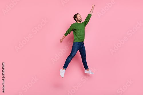 Full body portrait of carefree cheerful person raise arm look empty space hold umbrella isolated on pink color background