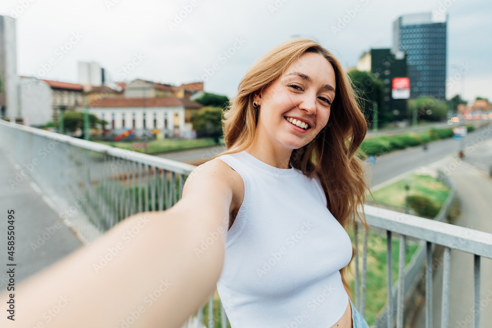 Young caucasian woman outdoor using smartphone taking selfie smiling happy