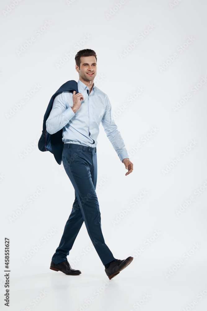 Smiling businessman holding his blazer and going Smiling businessman holding his blazer and going