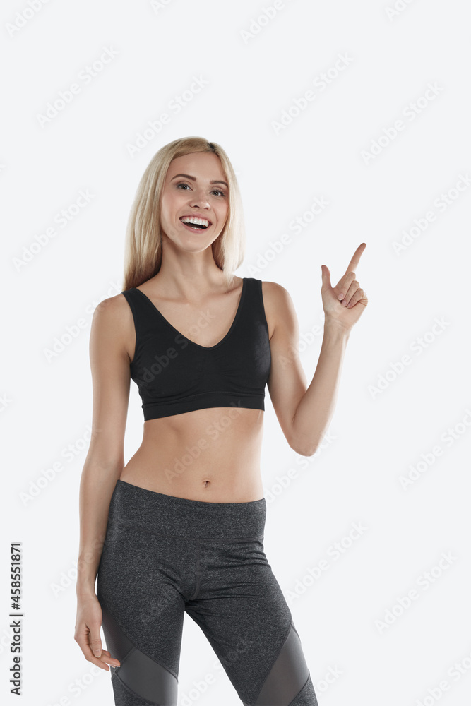 European smiling sports woman pointing with finger European smiling sports woman pointing with finger