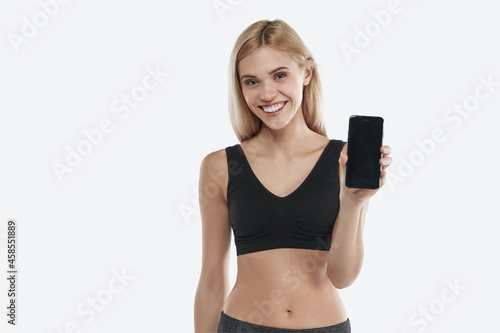 European smiling sports woman showing mobile phone