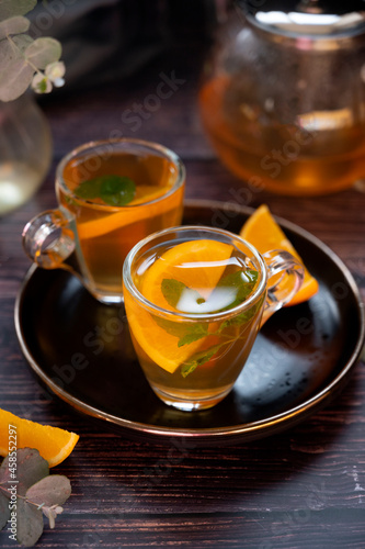 Hot tea in glass cups with lemon and eucalyptus leaves. Dark background.