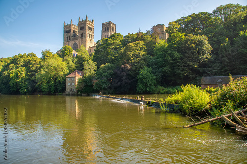 A view past a weir on the River Wear towards the cathedral in Durham, UK in summertime