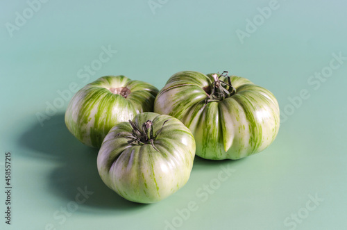 Green tomatoes on a light green background of the mine space. Large green tomatoes close up 
