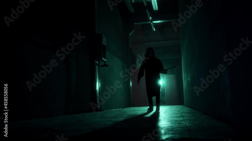 Maniac walking with axe in dark corridor. Mystical scary murderer going to kill, carrying murderous weapon. Halloween costume of killer. Horror scene or nightmare concept.  photo