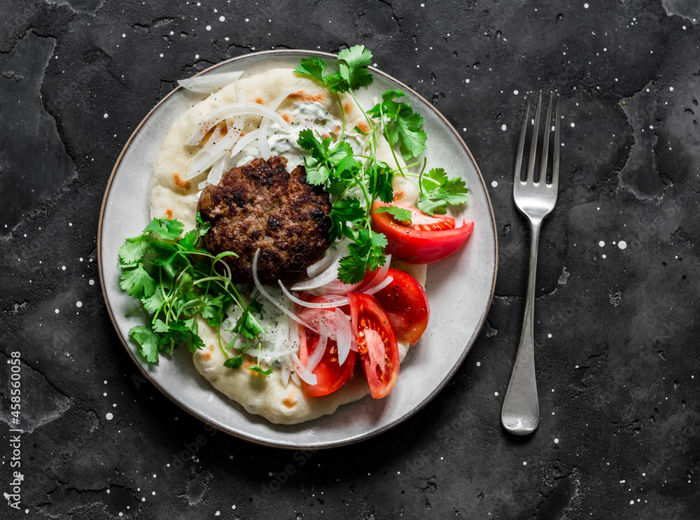 Unleavened flatbread with burger, yogurt sauce, fresh tomatoes and cilantro on a dark background, top view. Delicious tapas, snack Unleavened flatbread with burger, yogurt sauce, fresh tomatoes and cilantro on a dark background, top view. Delicious tapas, snack