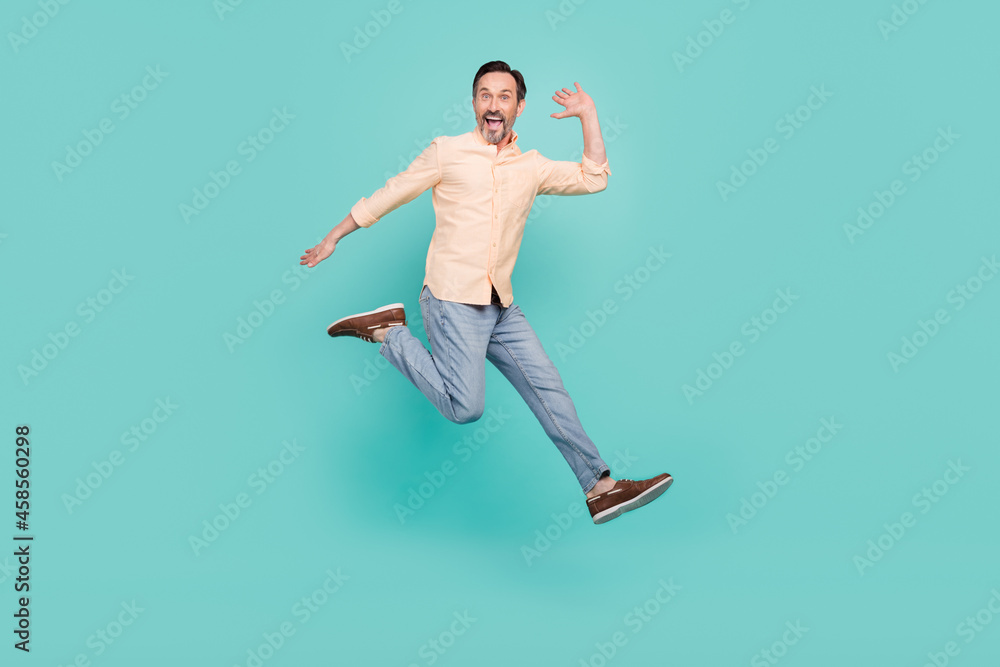 Full size photo of cool age man jump wear shirt jeans sneakers isolated on teal color background