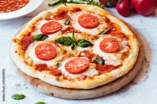 Classic Pizza with basil and tomato on top places on a bright background