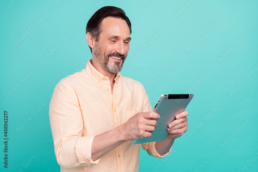 Photo of positive smiling handsome businessman working in tablet read new project isolated on teal color background Photo of positive smiling handsome businessman working in tablet read new project isolated on teal color background