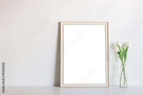 A blank picture frame with flowers on table.