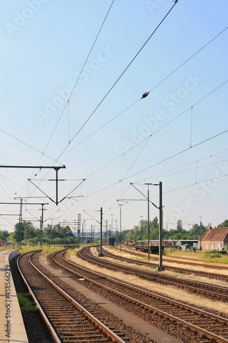 View of empty multiple train tracks from platform at Itzehoe train station in summer with clear and sunny blue sky background. No people. 