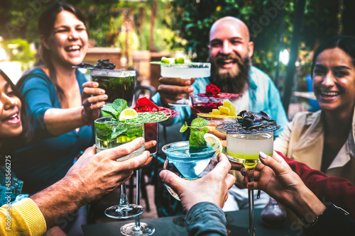 Fashionable people holding multicolored drinks - Trendy friends having fun together drinking cocktails at happy hour - Social gathering party time concept on vintage filter and shallow depth of field