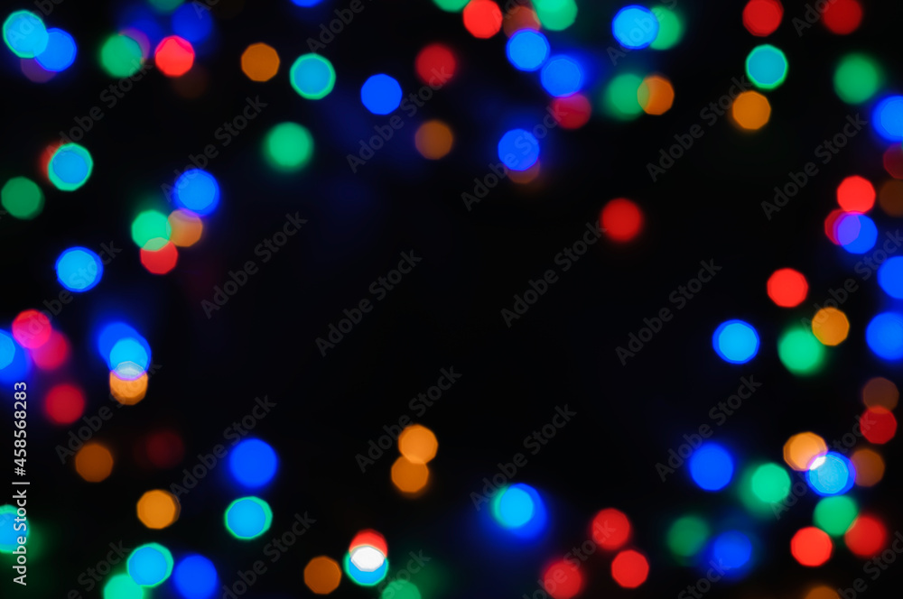 Bokeh, defocused colored lights forming a frame on a black background. Abstract festive background with copy space