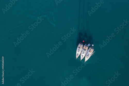 Aerial view to three small yachts in a deep blue sea.